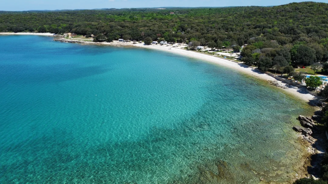 Turquoise Adriatic water and the tree-lined Bale Beach at Mon Perin, Istria