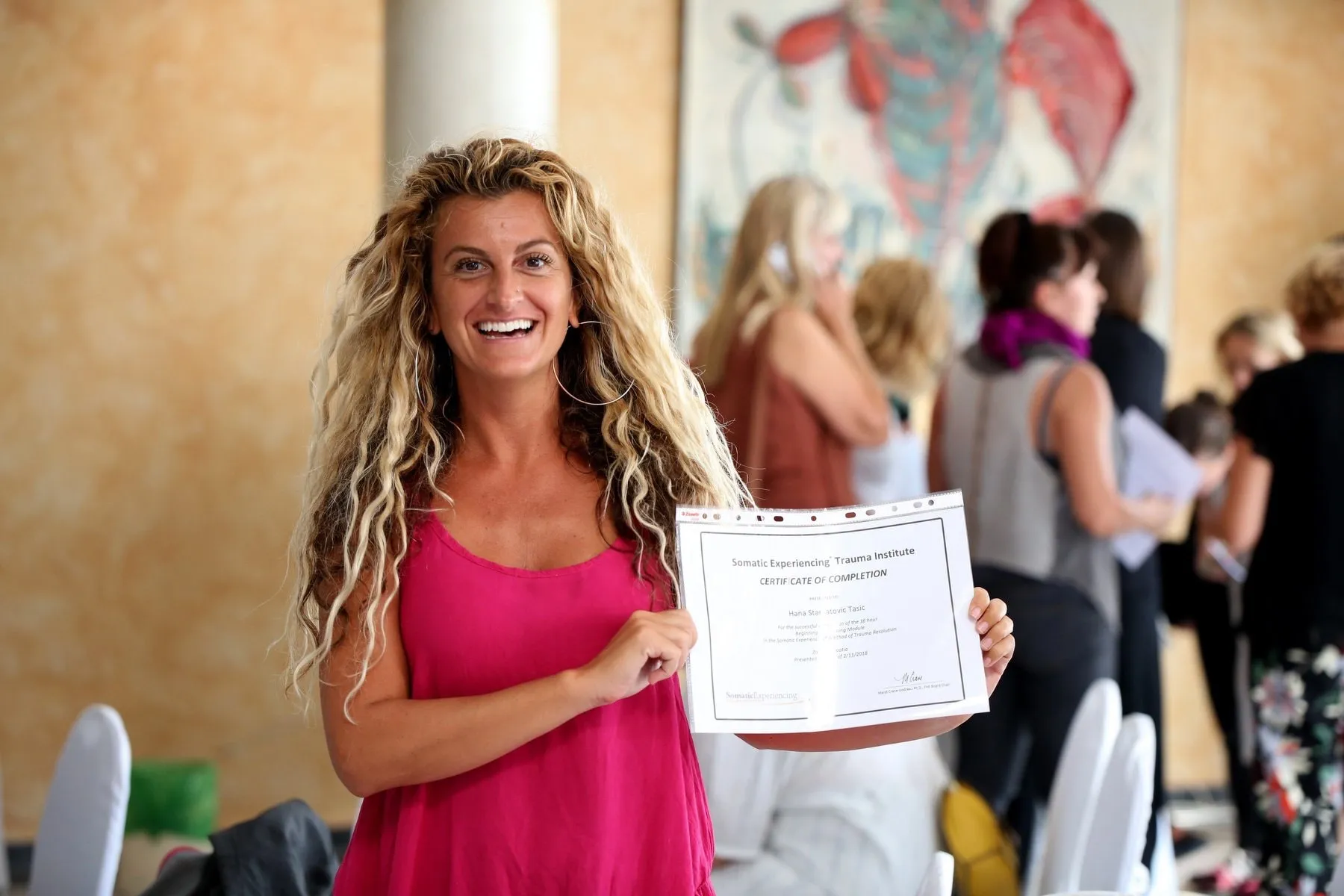 A smiling Somatic Experiencing participant holding her certificate of completion